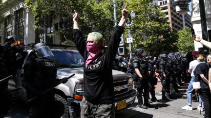 An unidentified Rose City Antifa member flicks off to the police during a demonstration between the left and right at Pioneer Courthouse Square on June 29, 2019 in Portland, Oregon.