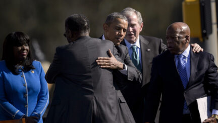US President Barack Obama hugs Rep. Bobby Rush while former US President George W. Bush and Rep. John Lewis talk at the Edmund Pettus Bridge on March 7, 2015 in Selma, Alabama.