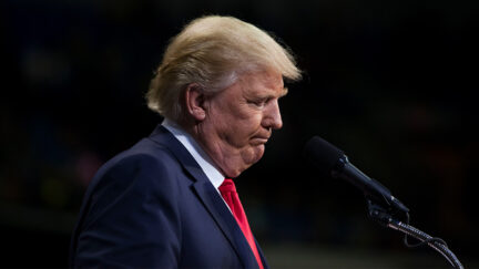 A bejoweled Trump looks down.