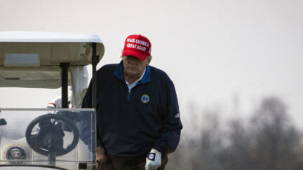 President Donald Trump climbs into golf cart