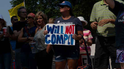 A woman holds a sign reading Will Not Compply as she joins hundreds of other demonstrators gathering to protest against mandated vaccines outside of the Michigan State Capitol on August 6 2021 in Lansing Michigan