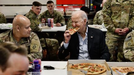 US President Joe Biden (C) eats a pizza as he meets with service members from the 82nd Airborne Division, who are contributing alongside Polish Allies to deterrence on the Alliances Eastern Flank, in the city of Rzeszow in southeastern Poland, around 100 kilometres (62 miles) from the border with Ukraine, on March 25, 2022. (Photo by Brendan SMIALOWSKI / AFP) (Photo by BRENDAN SMIALOWSKI/AFP via Getty Images)