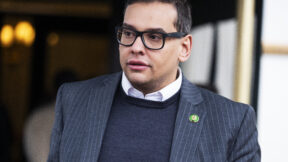 George Santos wearing a white shirt, blue sweater, and blue jacket