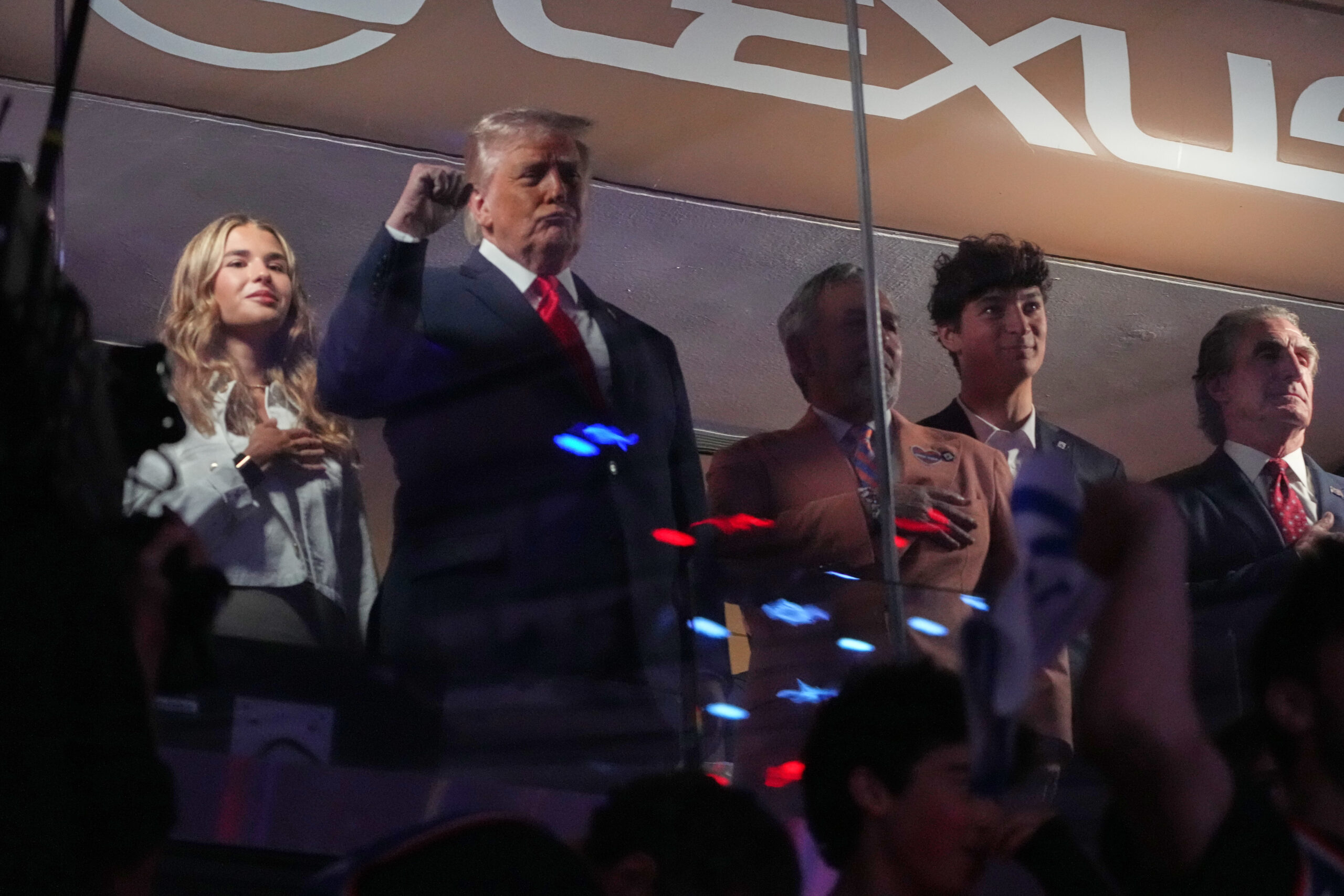President Donald Trump gestures during the National Anthem as he attends an NBA Finals playoff basketball game between the New York Knicks and the San Antonio Spurs at Madison Square Garden in New York, Monday, June 8, 2026, with Kai Trump, left, Knicks owner James Dolan and Interior Secretary Doug Burgum, right. (AP Photo/Mark Schiefelbein)