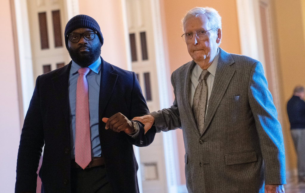 mitch mcconnell grips another man's arm as he walks