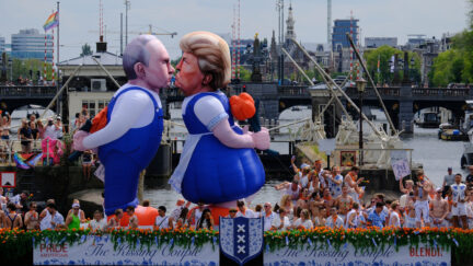 Two inflatable caricature balloons depicting U.S. President Donald Trump, center, and Russian President Vladimir Putin, left, as people line the Dutch capital's historic canals Saturday, Aug. 1, 2026, to watch the Amsterdam Pride Canal Parade. (AP Photo/Patrick Post)