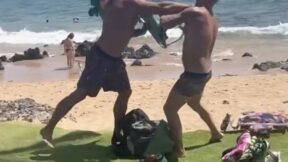 men brawling on hawaii beach